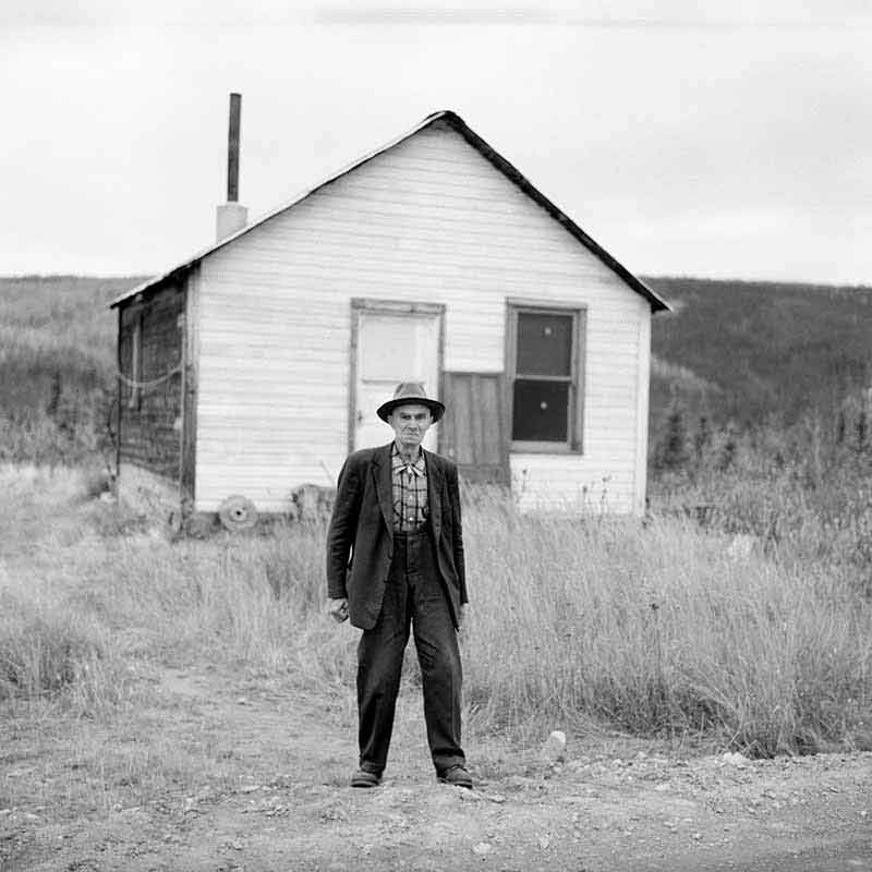 Gold Miner in Dawson Creek standing in front of his wooden house