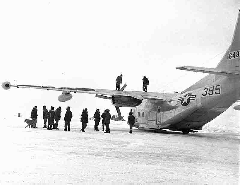 The crew of Alpha 2 has gathered around an Alaskan Air Command aircraft parked on the ice surface of Drift Station Alpha in the Arctic Ocean.