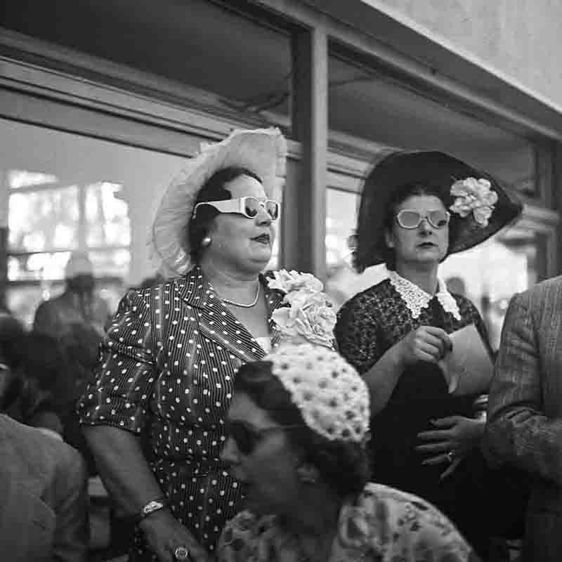 Fancy dressed ladies with hats and sunglasses at an event
