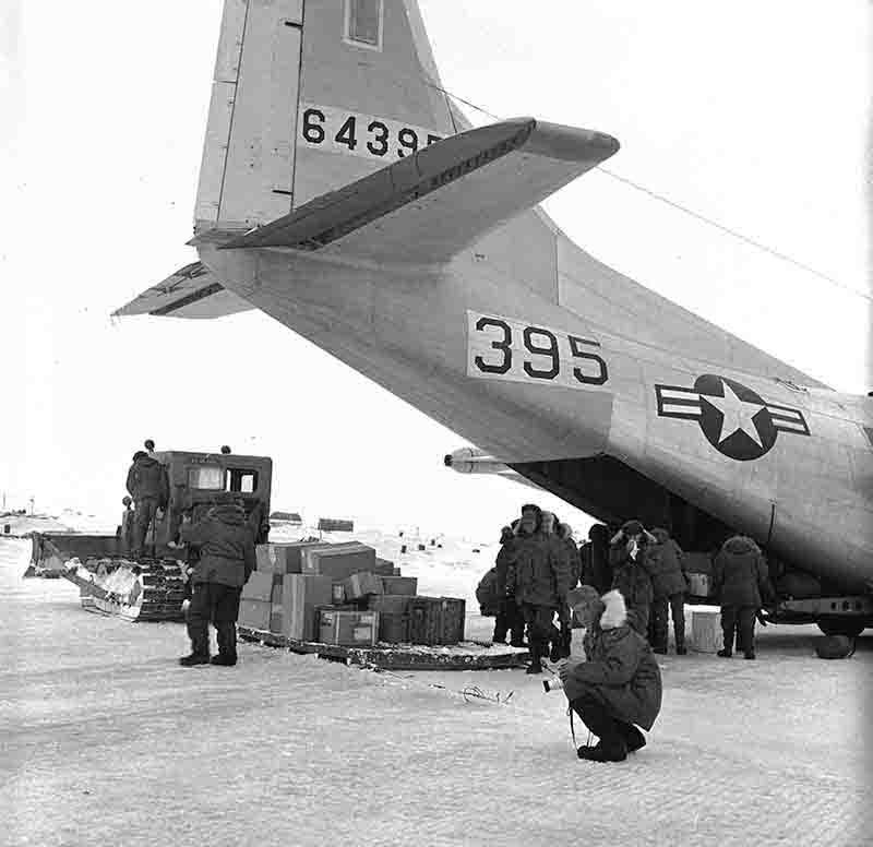 Alpha 2 crew gathered around an Alaskan Air Command aircraft parked on the ice surface of Drift Station Alpha in the Arctic Ocean.