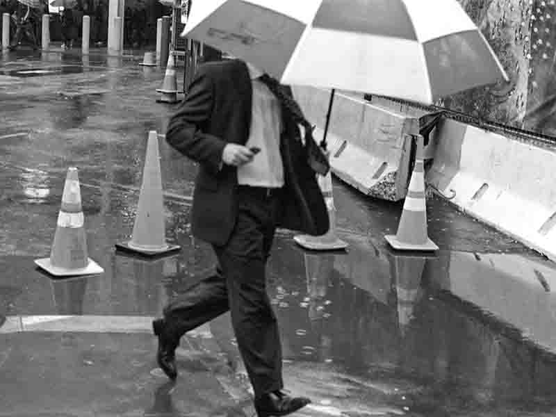Man with umbrella striding through the rain at Ground Zero, New York City