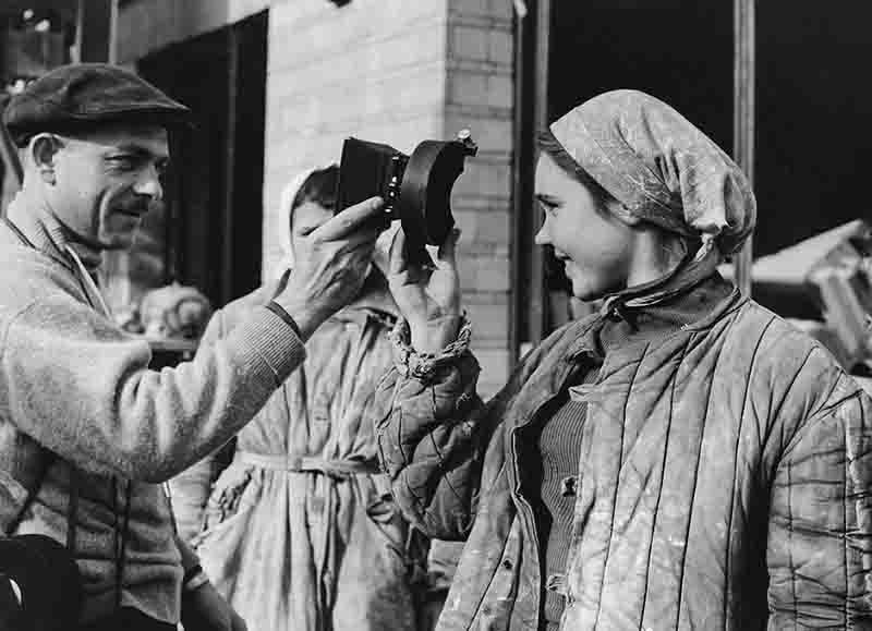 Western photographer handing a camera lens to a Russian lady in a gesture of politeness.