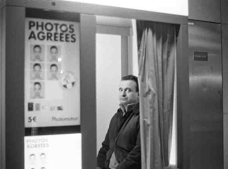 Photo dealer Serge Plantureux sitting in a public photo booth in Paris